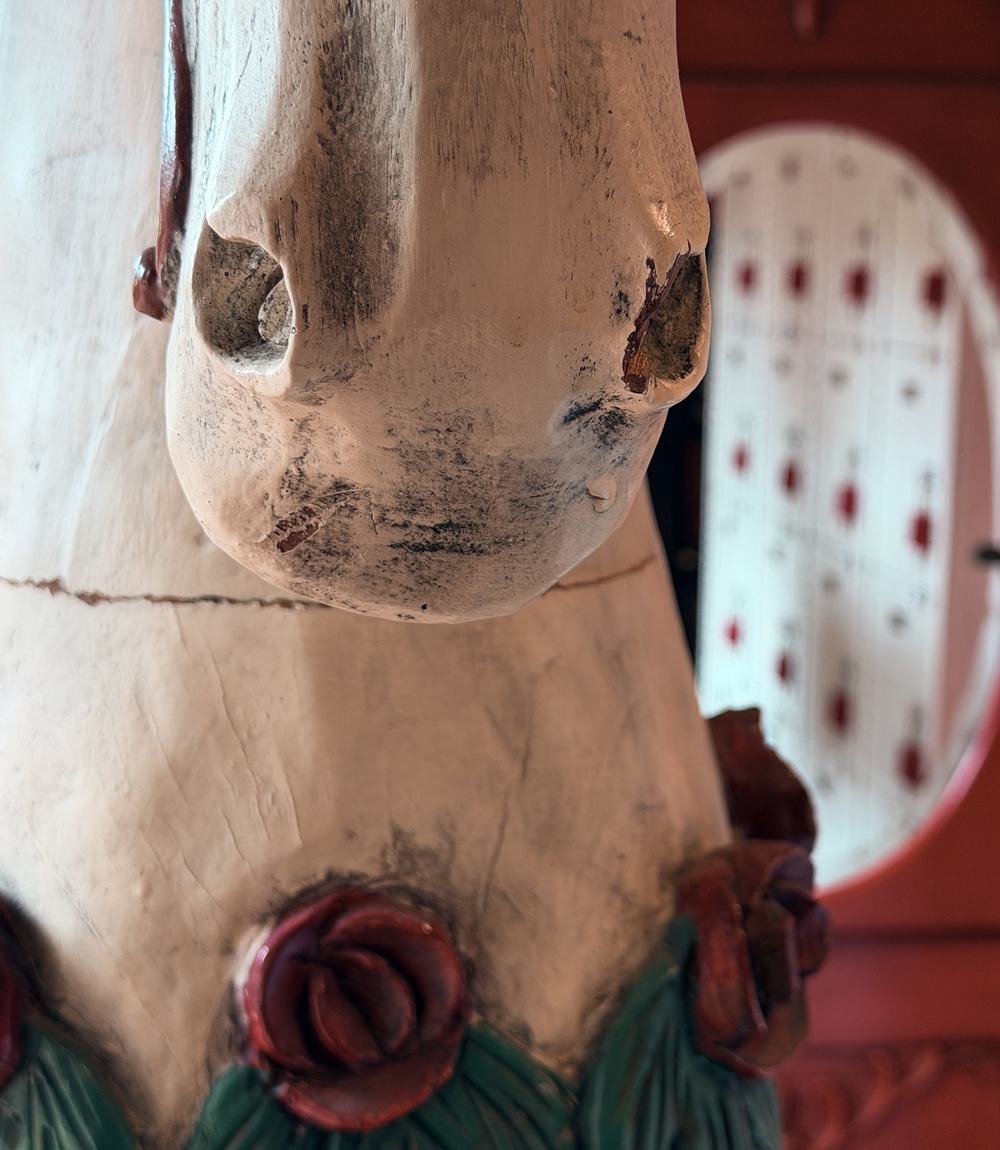 A carved wooden figure with painted roses